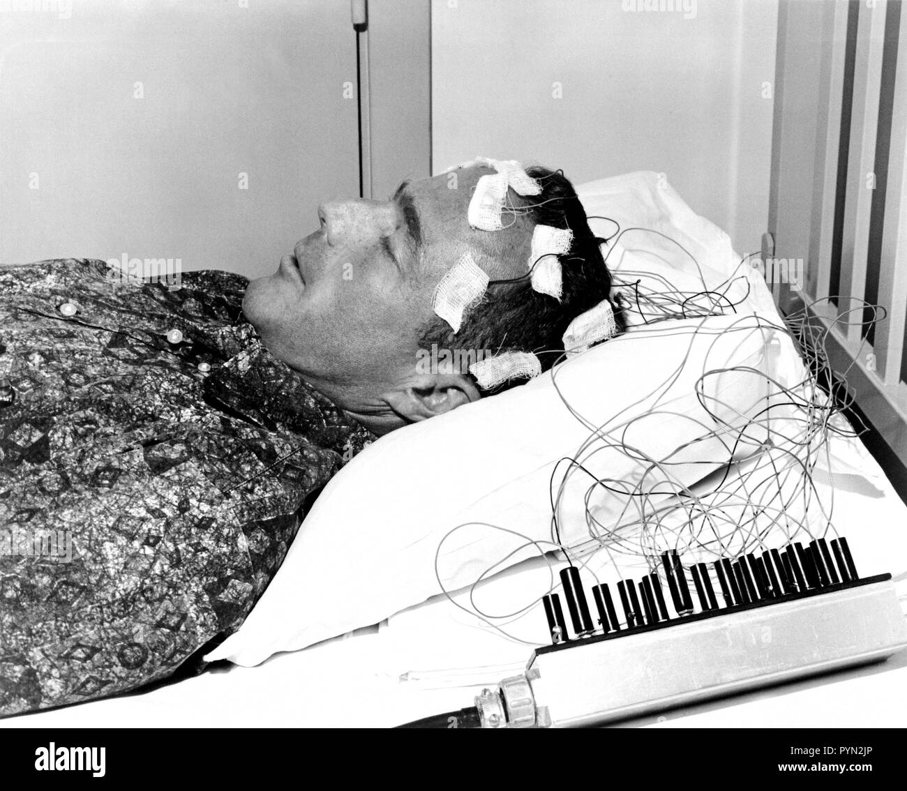 (1962) --- Mercury astronaut M. Scott Carpenter lies on a bed with biosensors attached to his head during astronaut training activities at Cape Canaveral Stock Photo