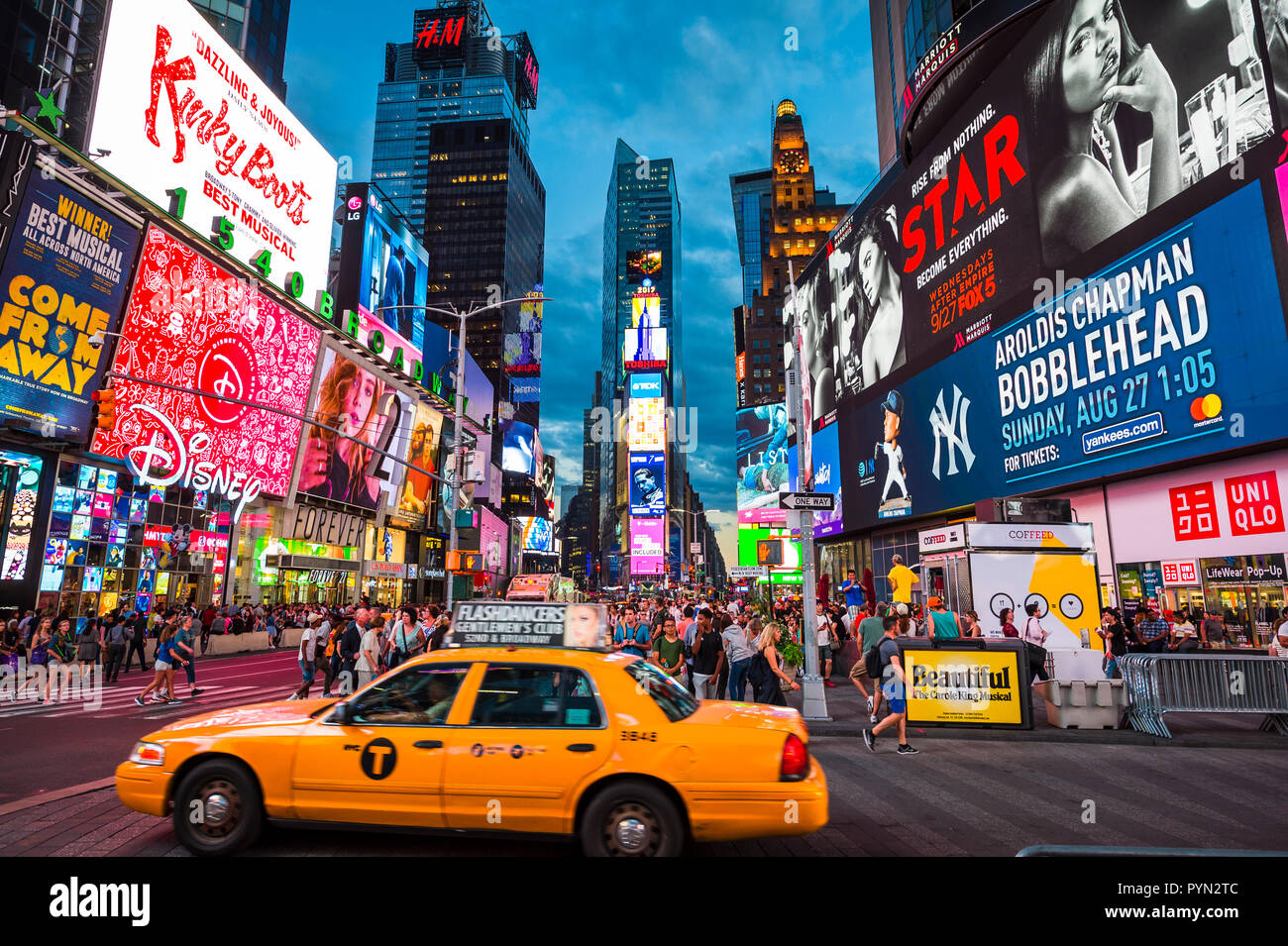 NEW YORK CITY - CIRCA AUGUST, 2018: Yellow taxis with on-board billboards compete for attention with the flashing signs of Times Square. Stock Photo