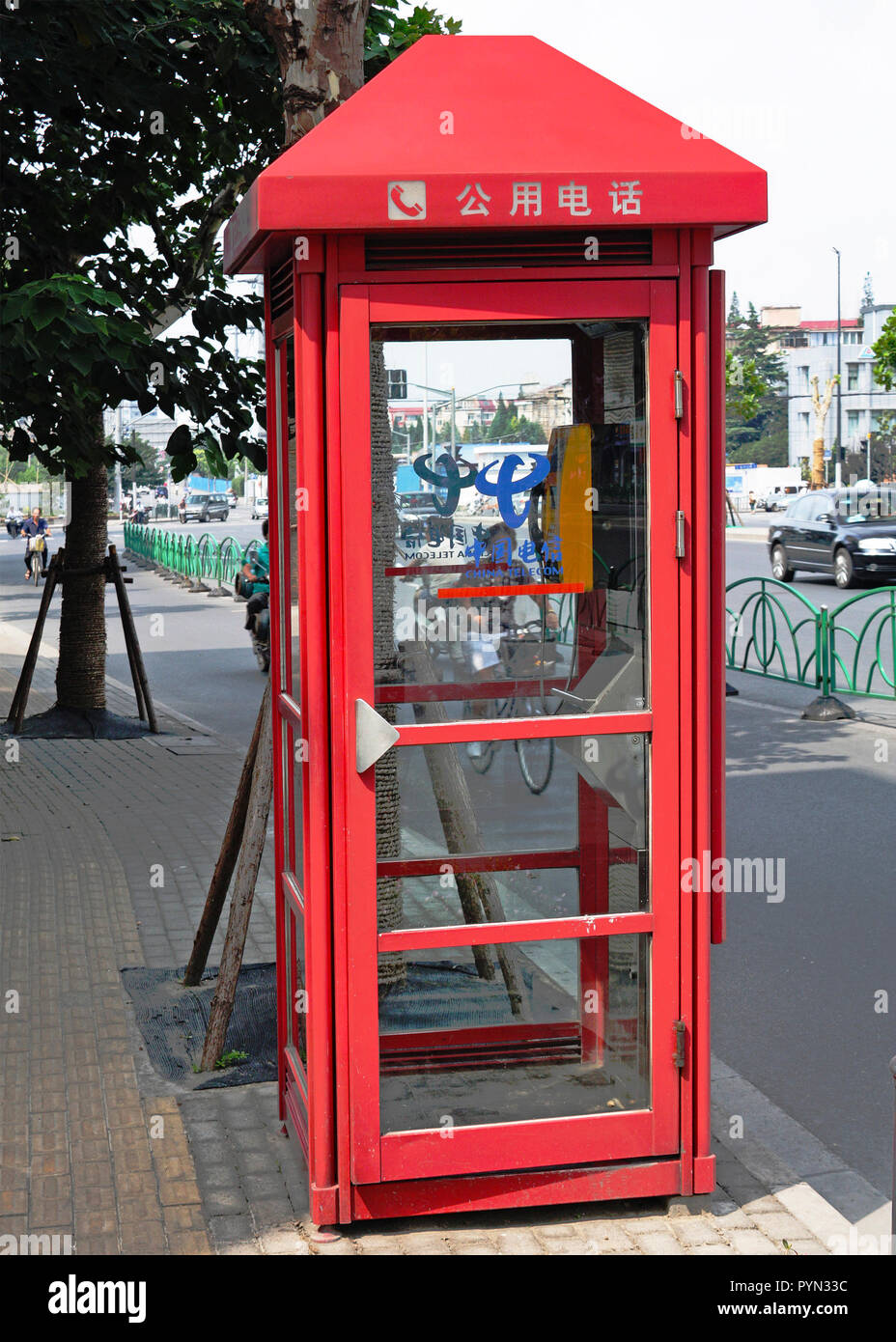 Public telephone box situated on pavement alongside a main road, Shanghai, China Stock Photo