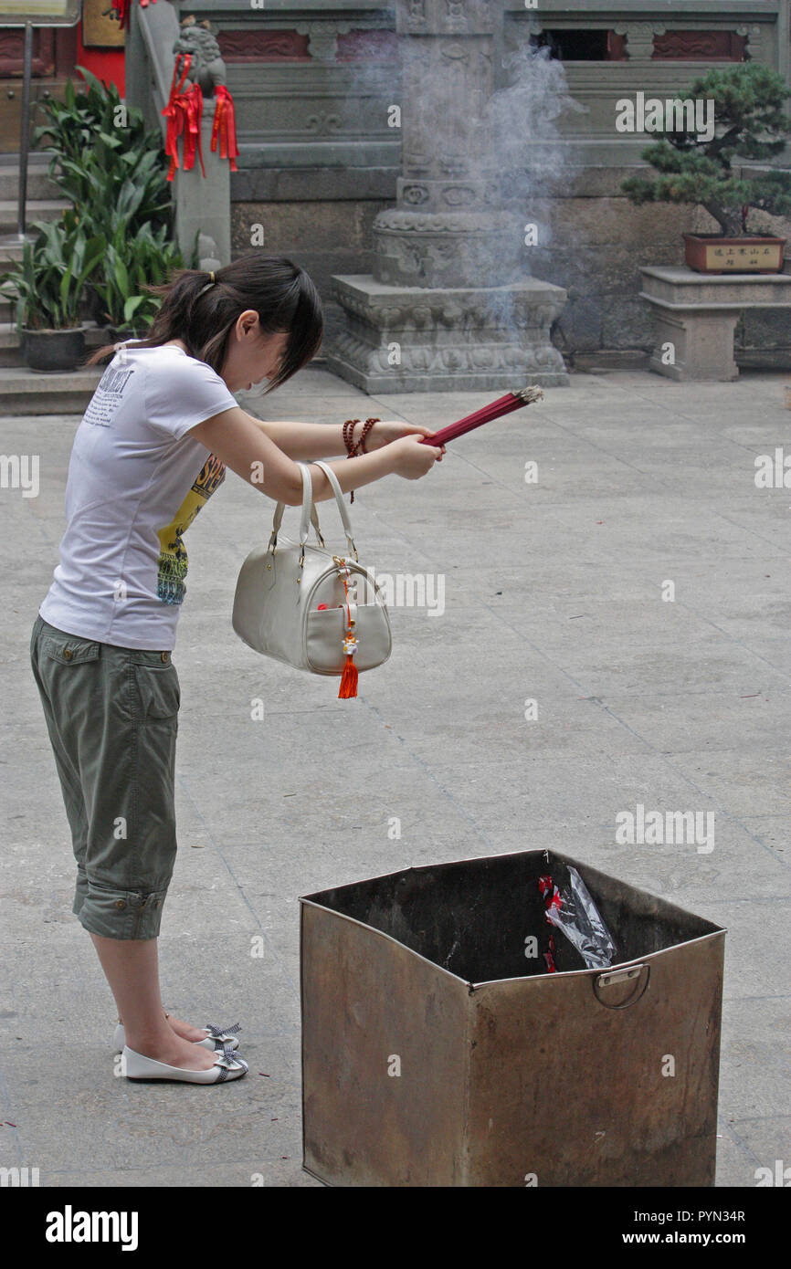 Young Chinese woman offering prayers and wishes, Jing'an Temple, Shanghai, China Stock Photo