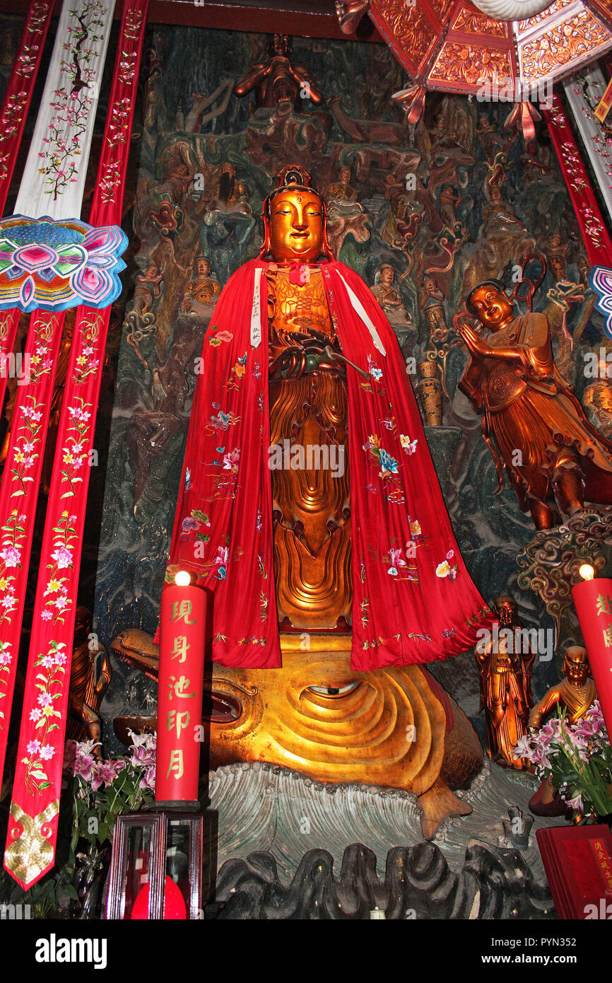 Jade Temple Buddha statue in red robe featuring multicoloured symbols and standing on serpent's head, Shanghai, China Stock Photo