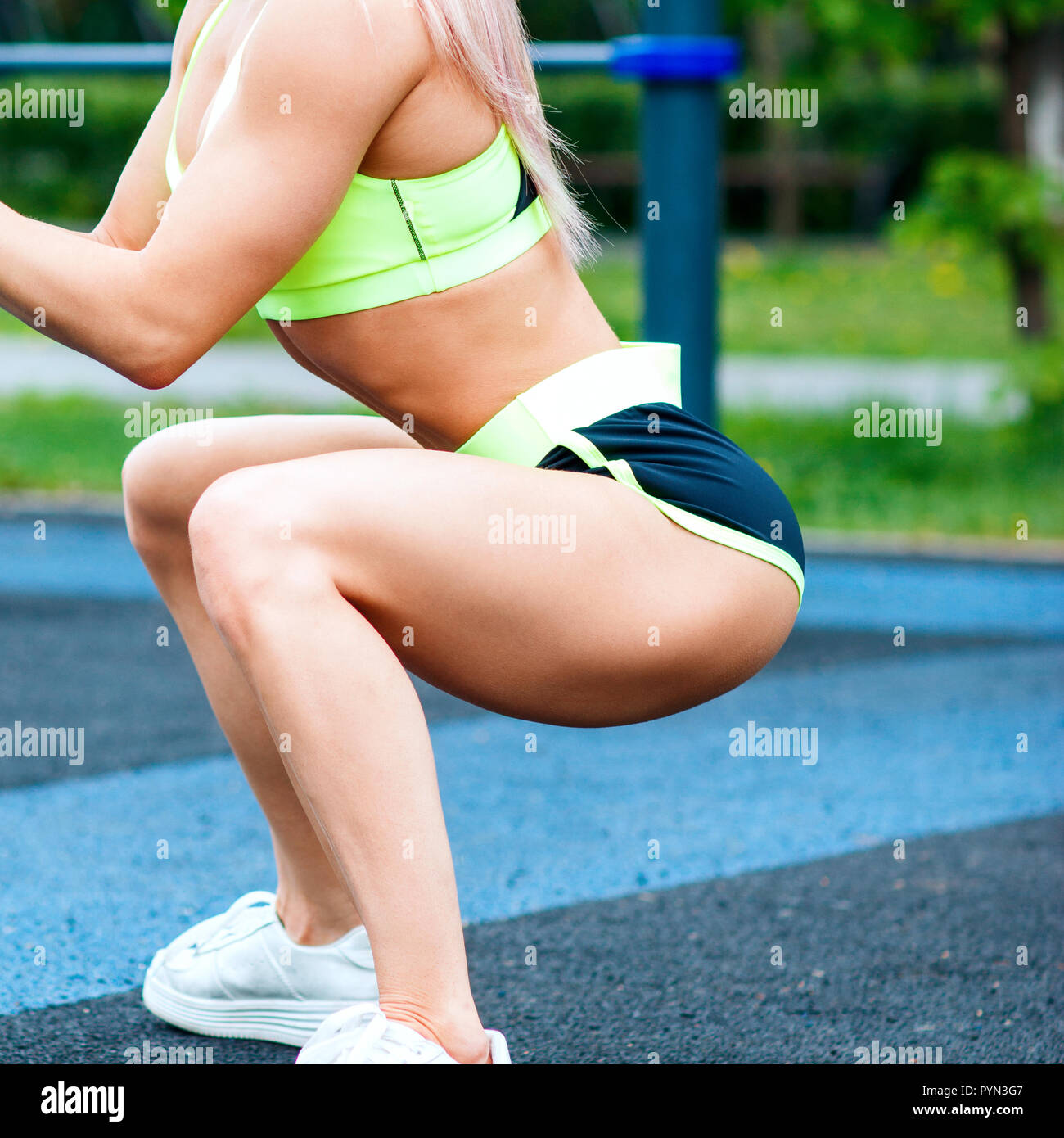 Sports girl in sportswear squatting in the summer park. Stock Photo