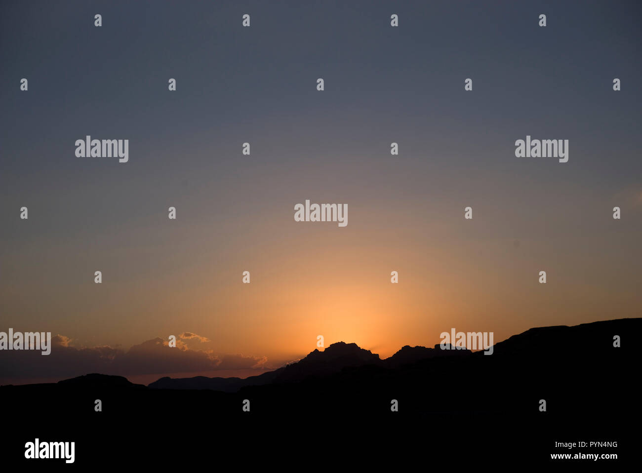 The evening sun sets over the Jabal Al-Madbah mountains in the desert at Petra, in Jordan, October 29, 2018. Stock Photo