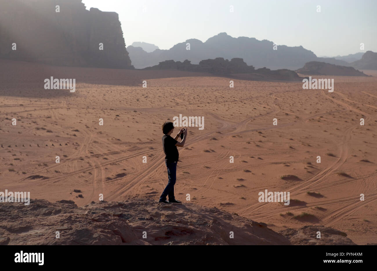 A Chinese tourist takes photographs of Wadi Rum in Jordan, October 30, 2018. Stock Photo