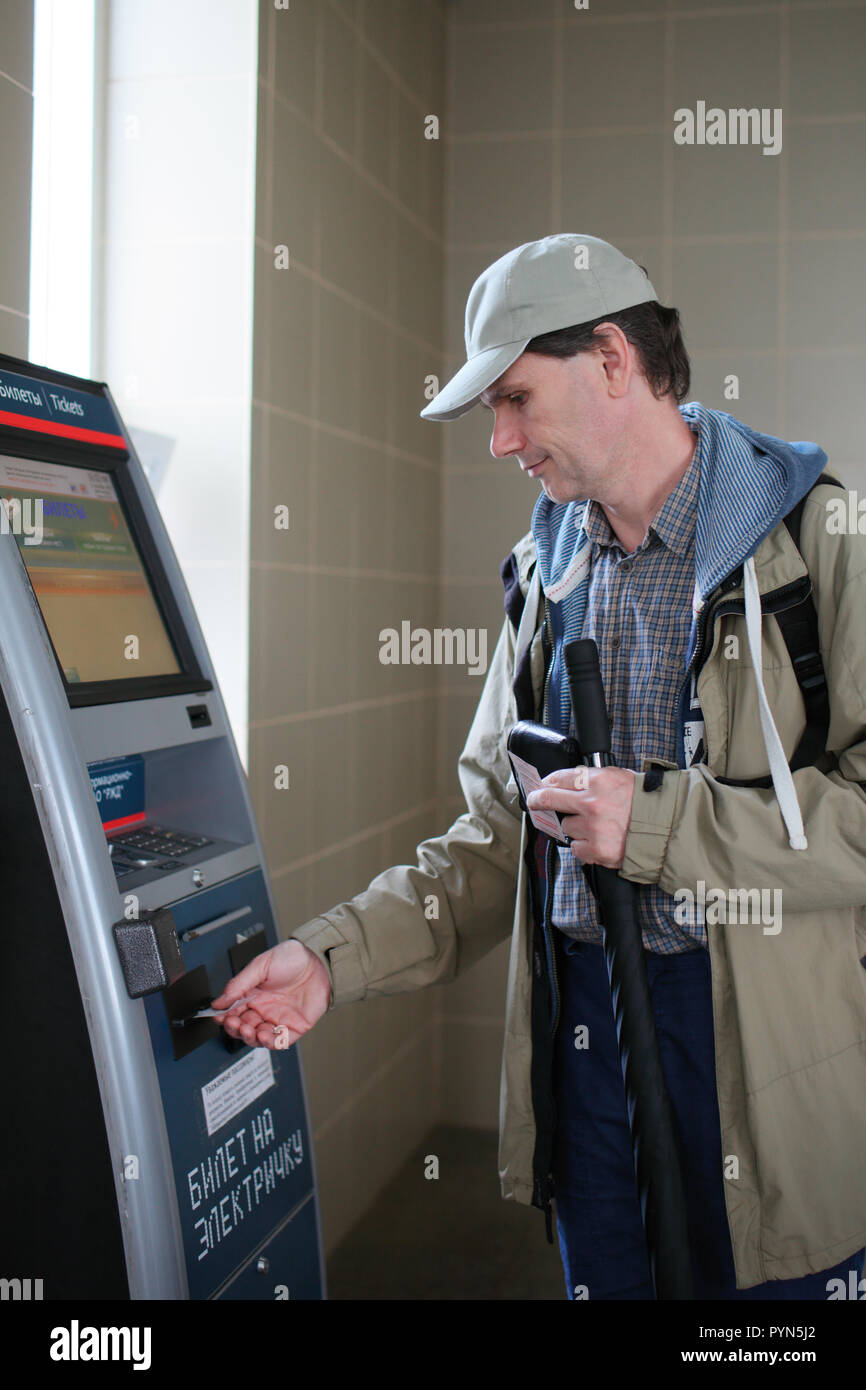 Zelenogorsk, Russia - September 11, 2016: Man buying commuter train ticket in a ticket vending machine. The ticketing machines accepting credit cards  Stock Photo