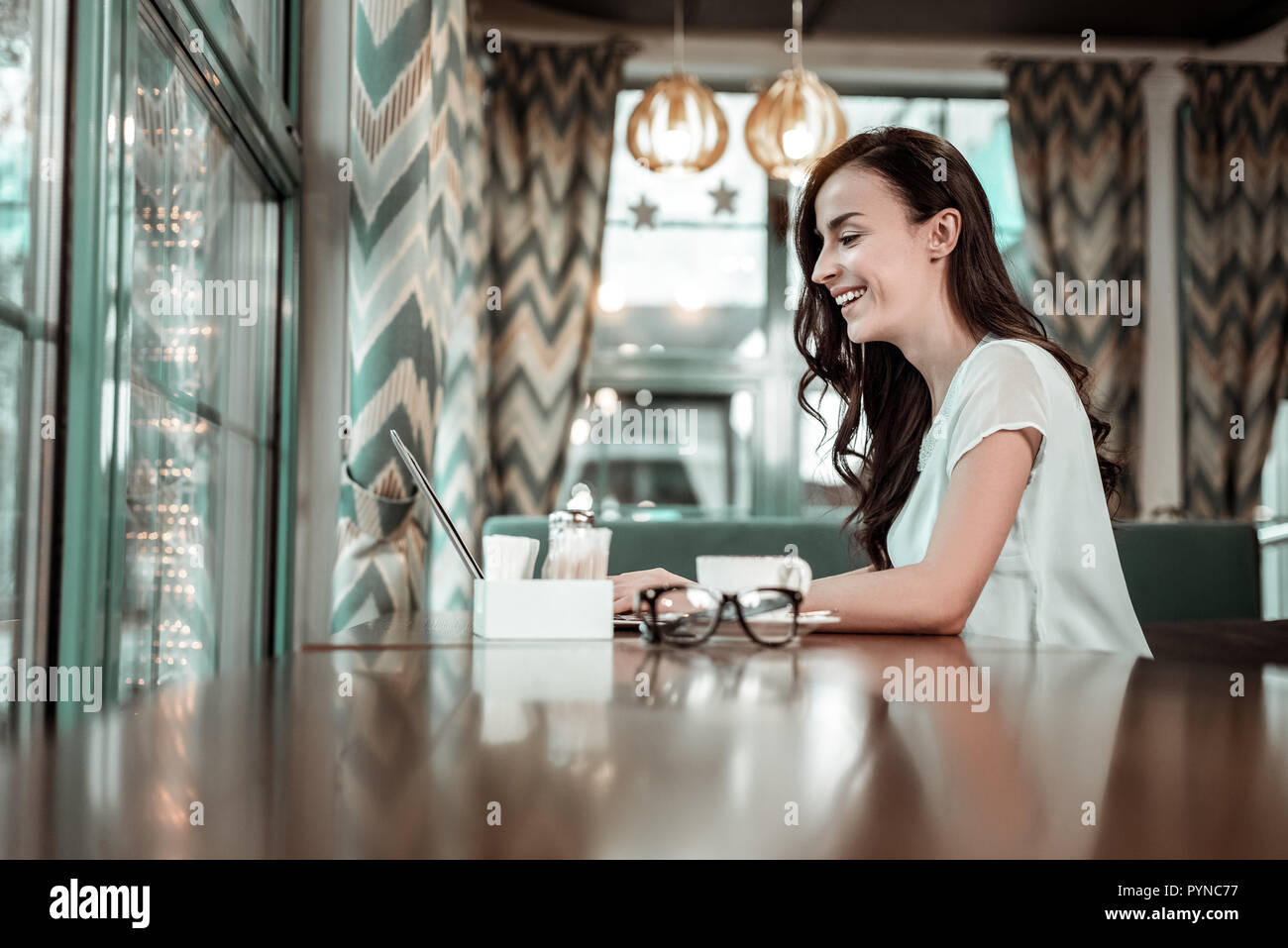Cheerful female person sitting in semi position in cafe Stock Photo