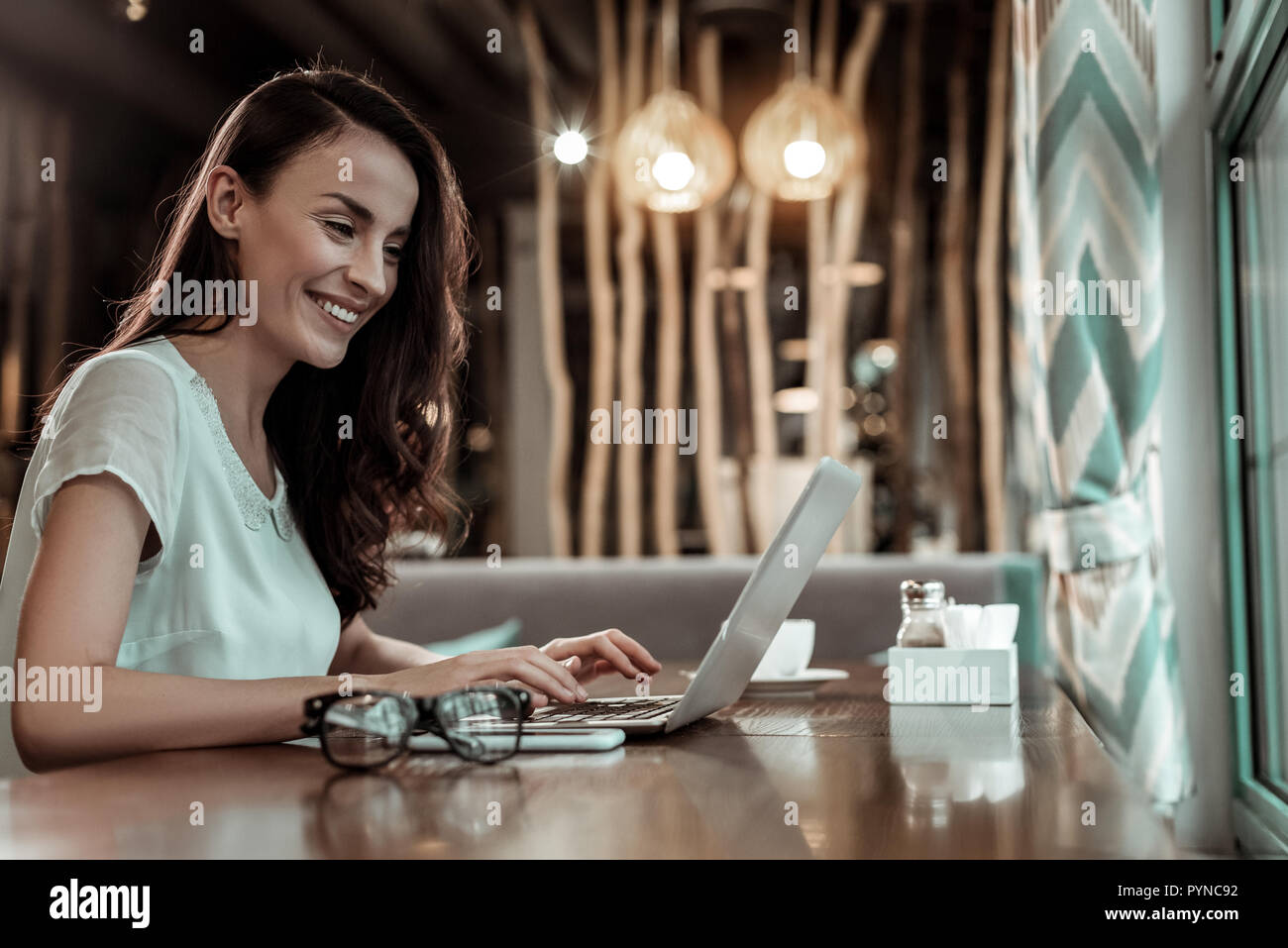 Beautiful brunette female working with pleasure in cafe Stock Photo
