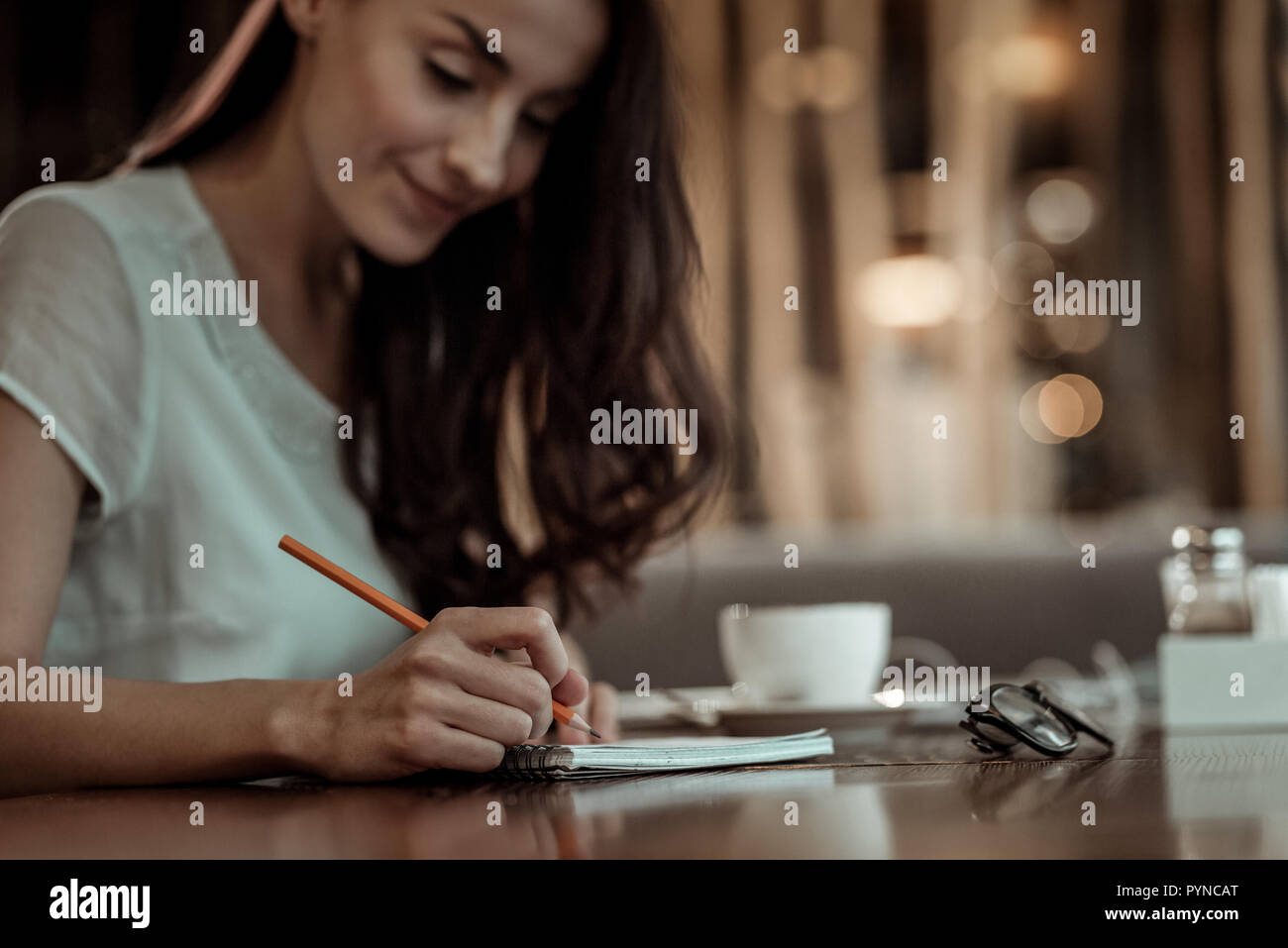 Concentrated brunette bowing head while writing notices Stock Photo