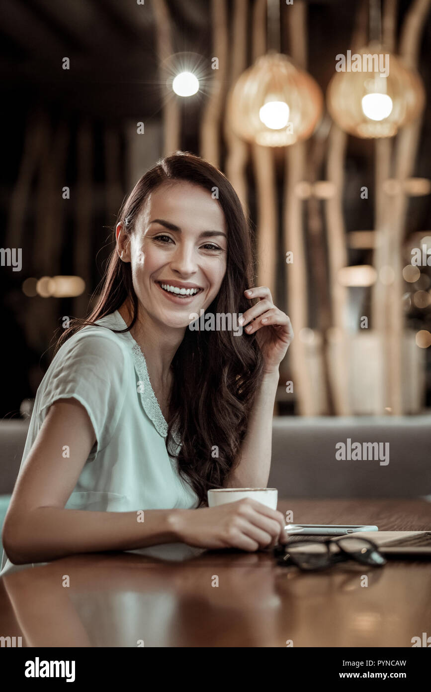 Pleased young woman visiting her favorite cafe Stock Photo