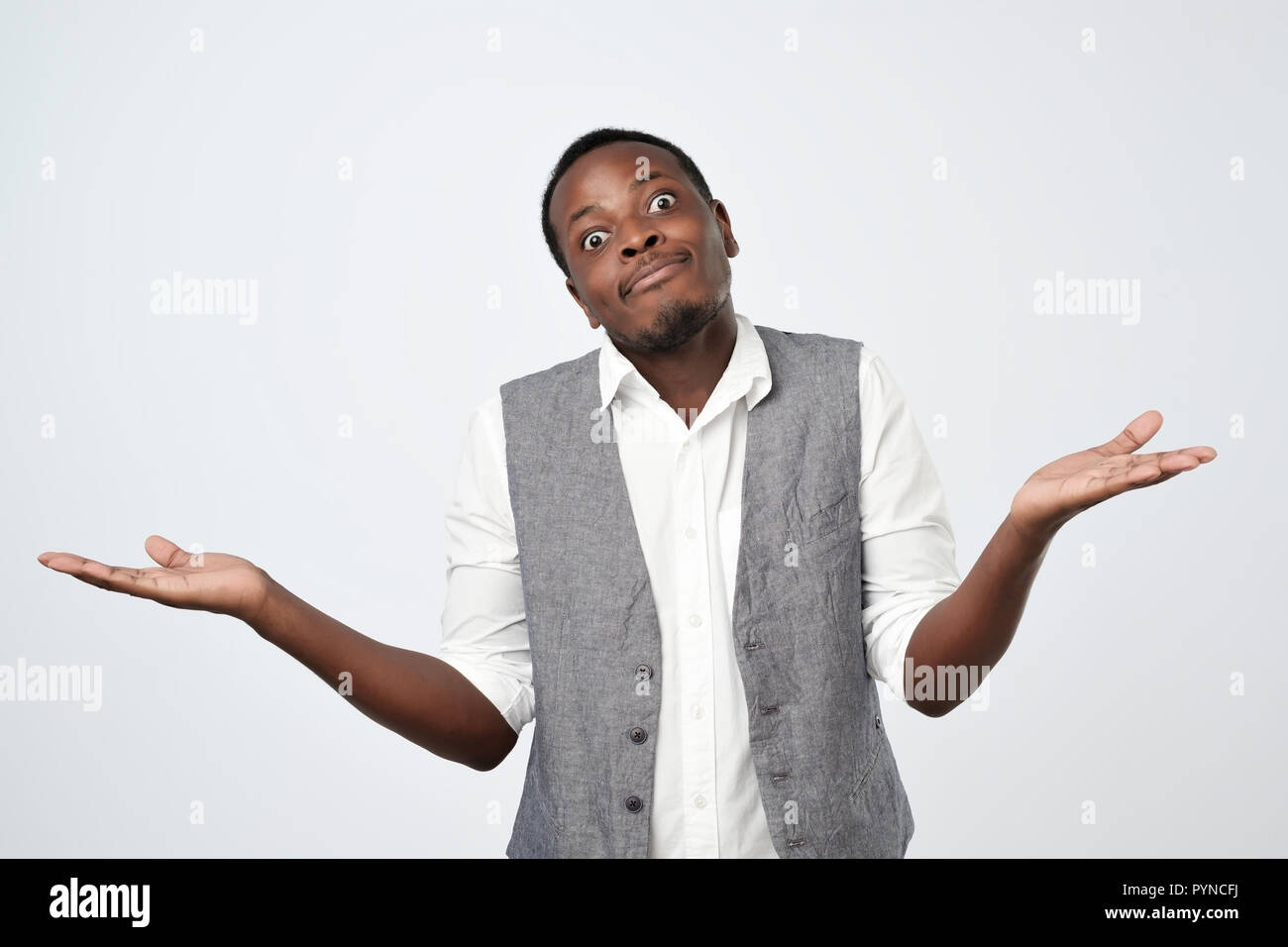 doubtful african man shrugs shoulders with confusion Stock Photo