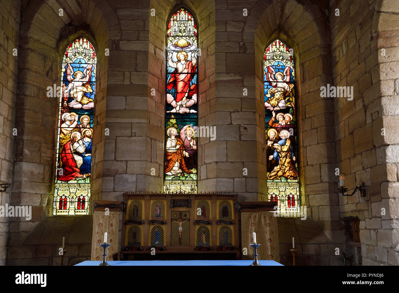 The Parish Church of Saint Mary the Virgin altar with stained glass windows depicting Ascension of Jesus Holy Island of Lindisfarne England UK Stock Photo