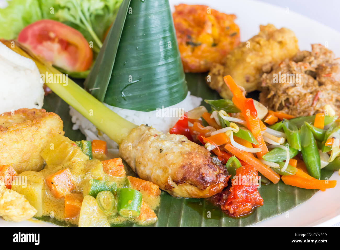 Nasi Campur Bali with tempeh, chicken and vegetables, served on a banana leaf Stock Photo