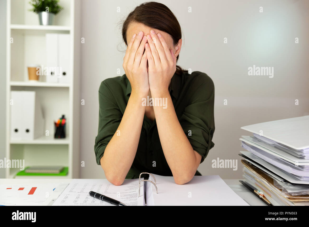 Businesswomen hiding behind her hands in an office. Business finance concept. Stock Photo