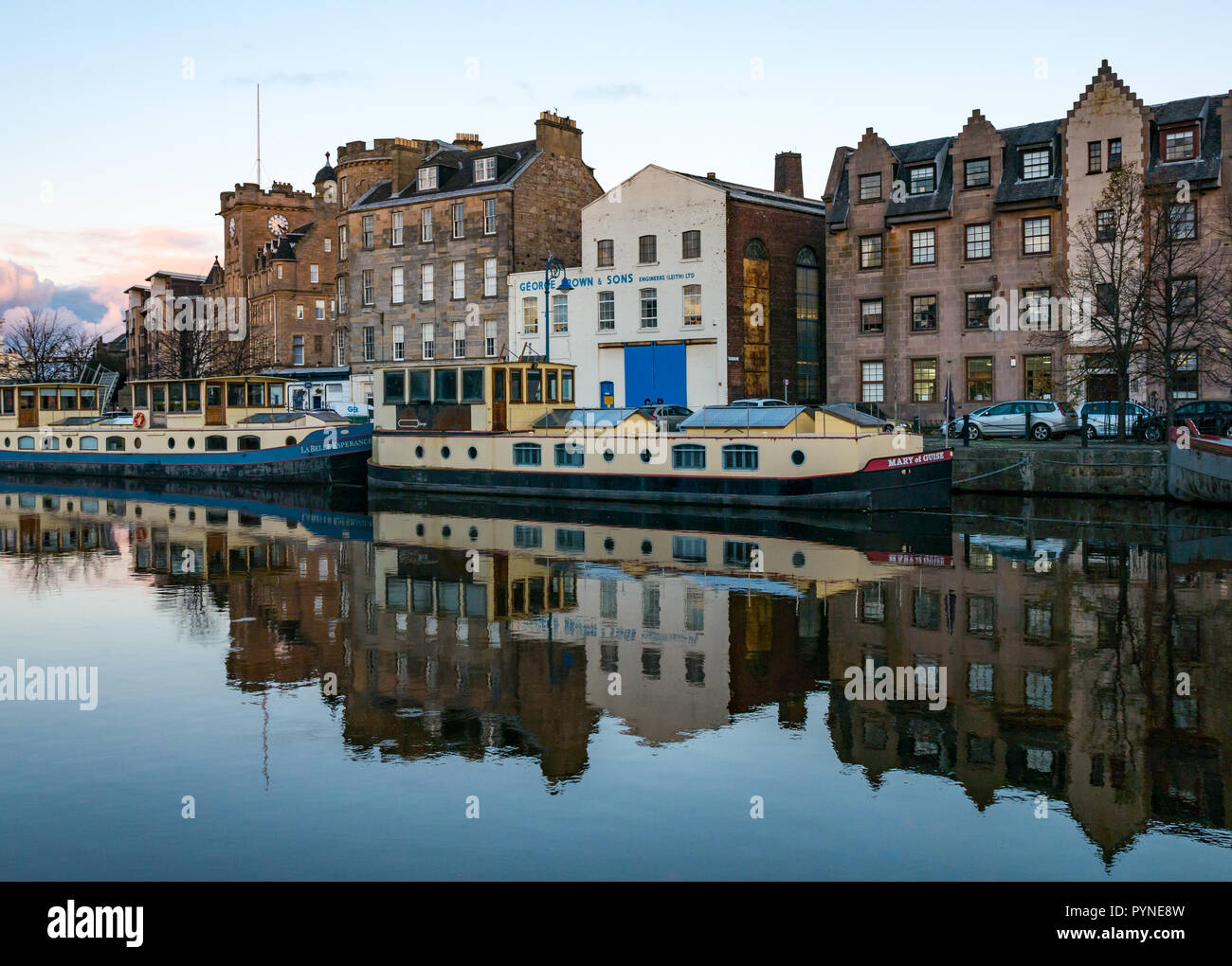 River barges with reflections moored on riverbank, The Shore, Water of Leith, Edinburgh, Scotland, UK at twilight Stock Photo
