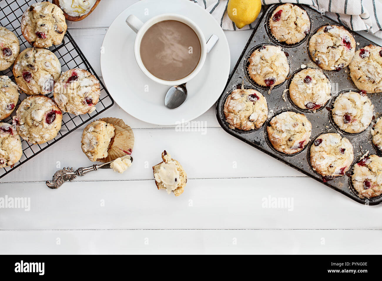 Hot steaming coffee and cranberry muffins with butter over a rustic white table  background. Image shot from above with free space for text. Stock Photo