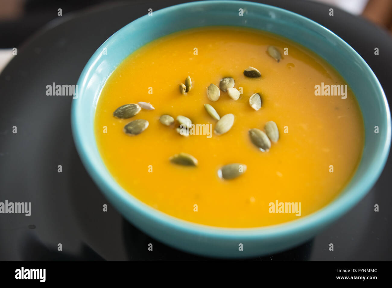 Blue bowl with pumpkin soup seasoned with seeds Stock Photo