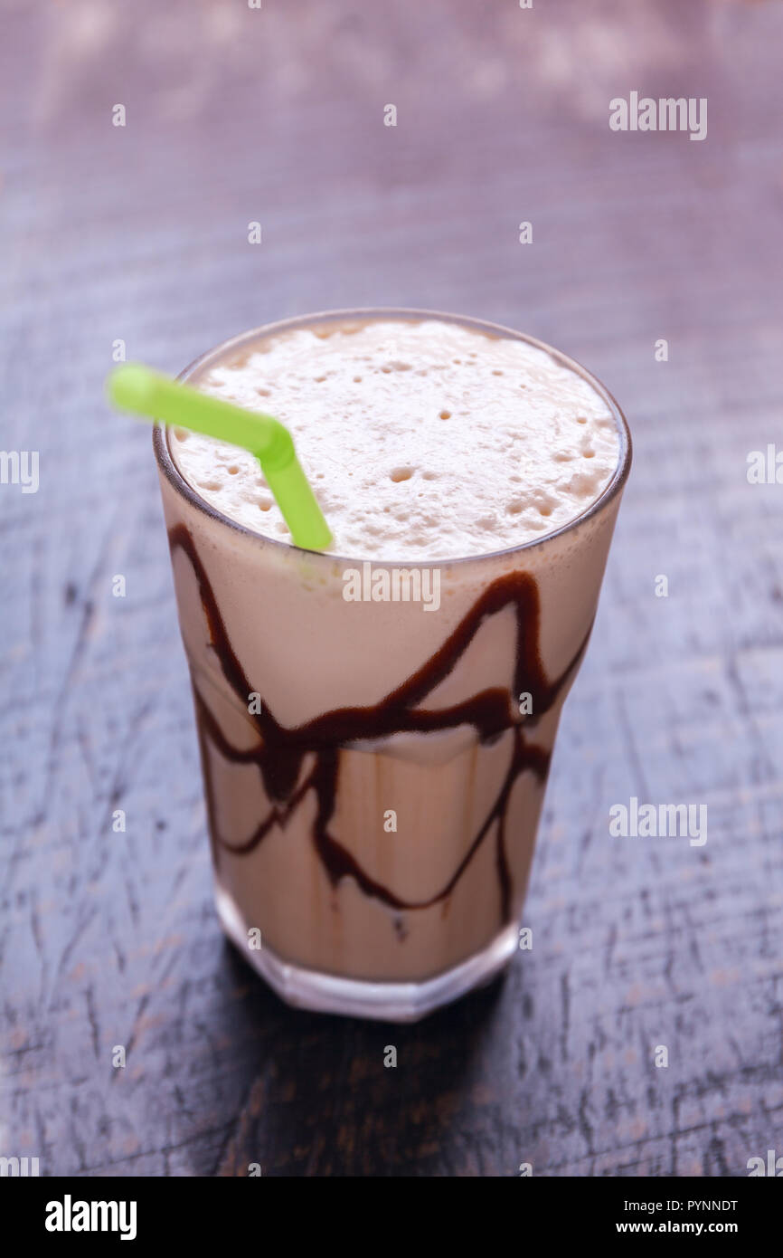 White Frappe Coffee Glass with iced drink on a dark wooden table in a ...