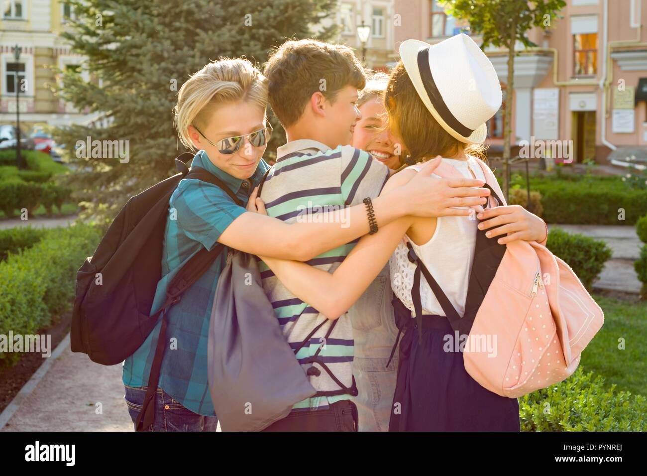 Group of happy teenagers 13, 14 years walking along the city street, friends embrace. Friendship and people concept Stock Photo