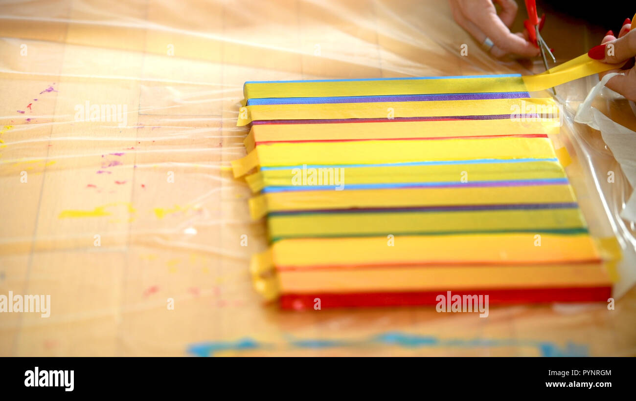 Female artist painting a rainbow with acrylic colors on canvas, hoe made art, DIY tutorial, colorful, mask taping painting for gold guilding Stock Photo