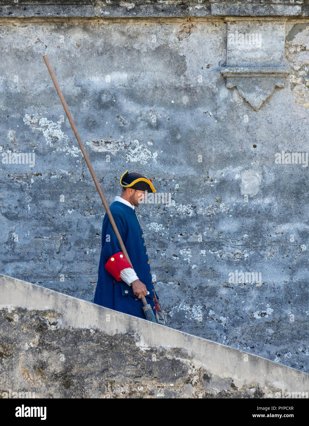 Soldier in Spanish period military costume descending steps with his tamping rod at Castillo de San Marcos St Augustine Florida USA Stock Photo