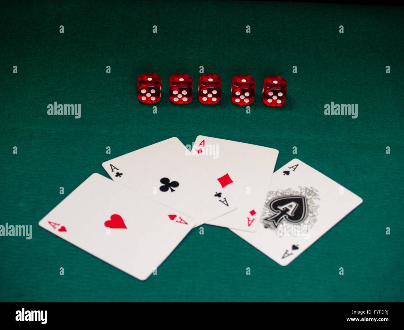 The four aces of a poker deck and several dice on a green mat Stock