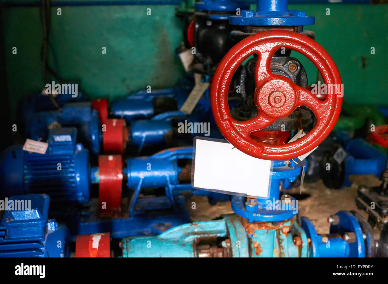 Older black with red latch handles on the cold water pipe colored in blue. Stock Photo