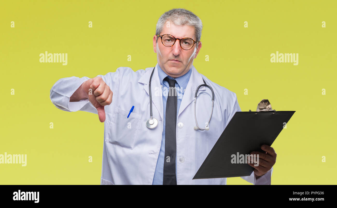 Handsome senior doctor man holding clipboard over isolated background ...