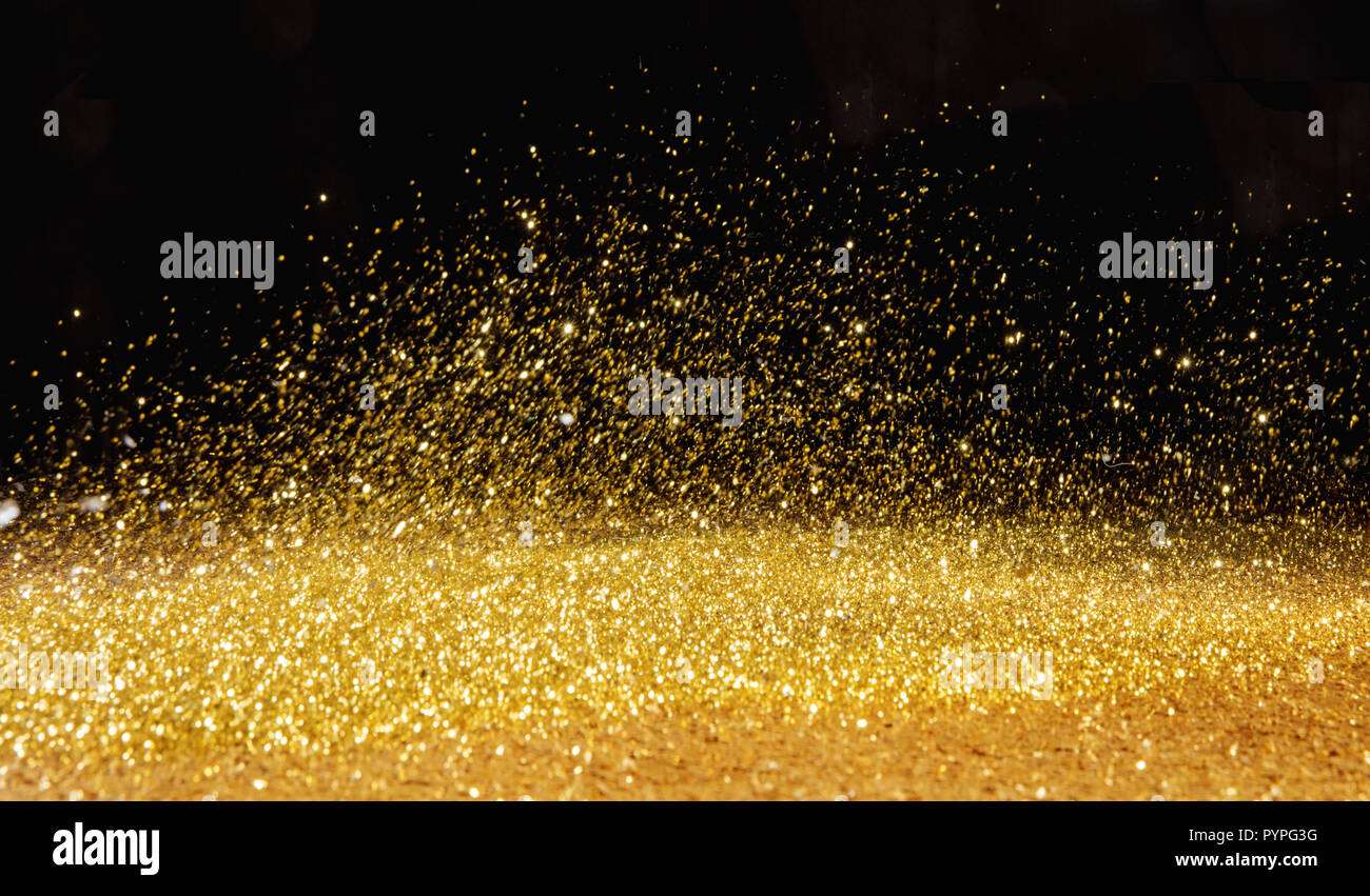 Golden, shining powder scattered over the dark background Stock Photo