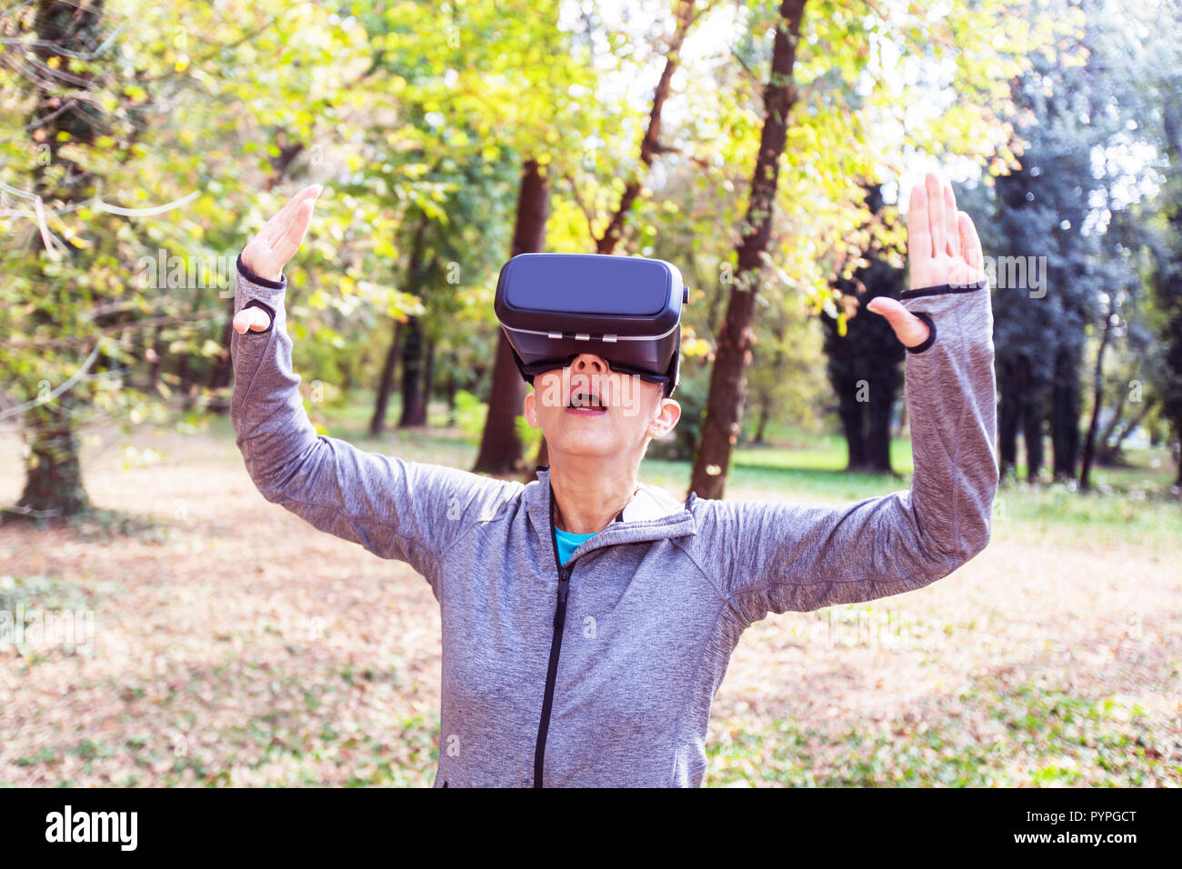 Surprised Senior woman fun with virtual reality headset in forest, VR