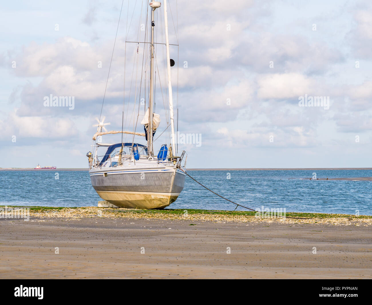 Sailing boat dried out at low tide of Wadden Sea on beach of nature reserve Boschplaat on Frisian island Terschelling, Netherlands Stock Photo