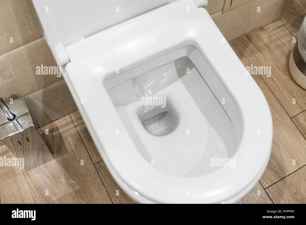 White toilet bowl in a bathroom. Closeup view of a flushing white toilet. The water swirls in