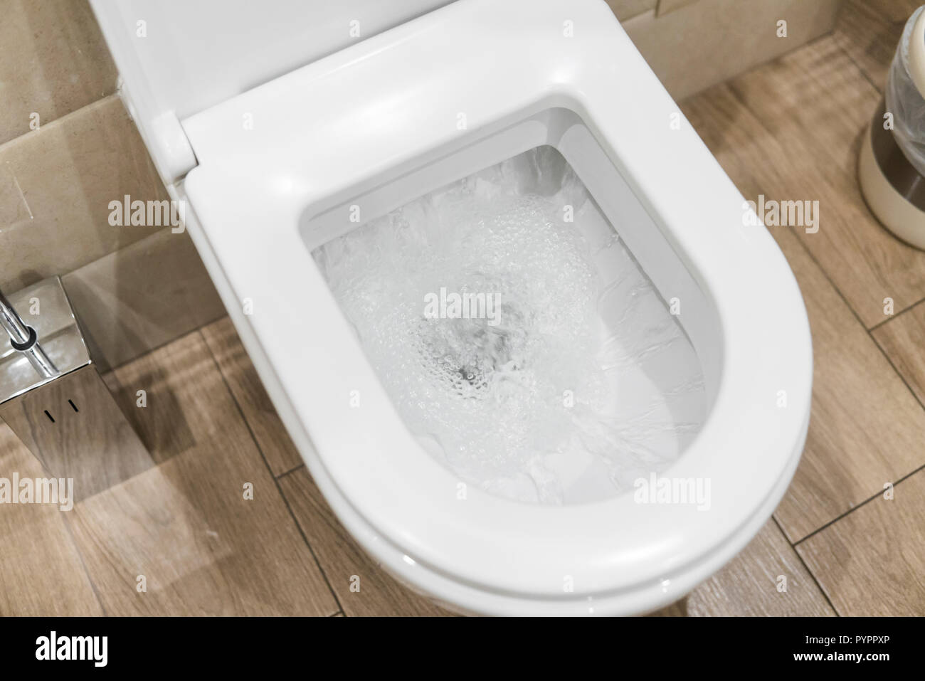 White toilet bowl in a bathroom. Closeup view of a flushing white