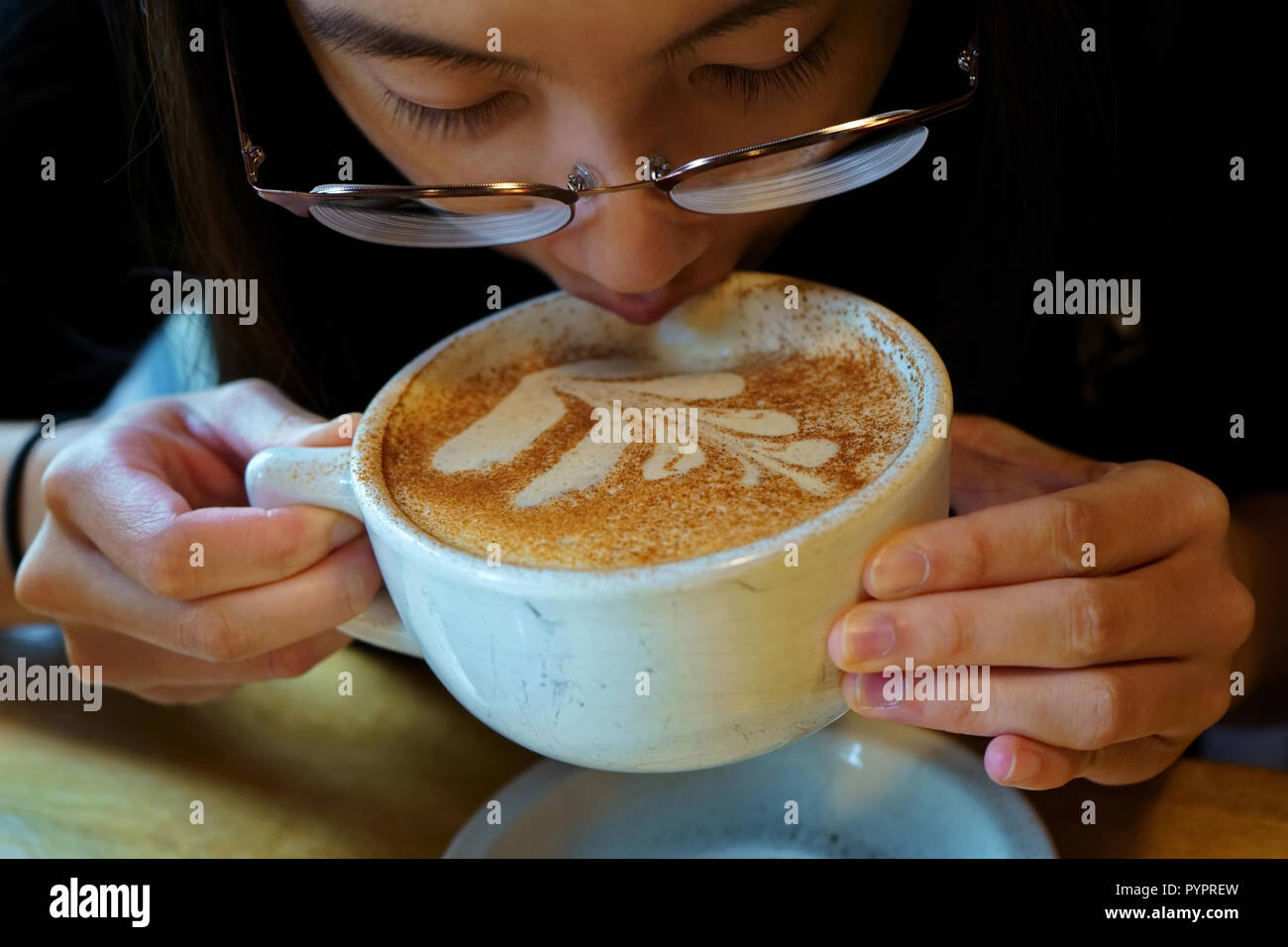 Young lady enjoying a nice art decorated latte. Stock Photo