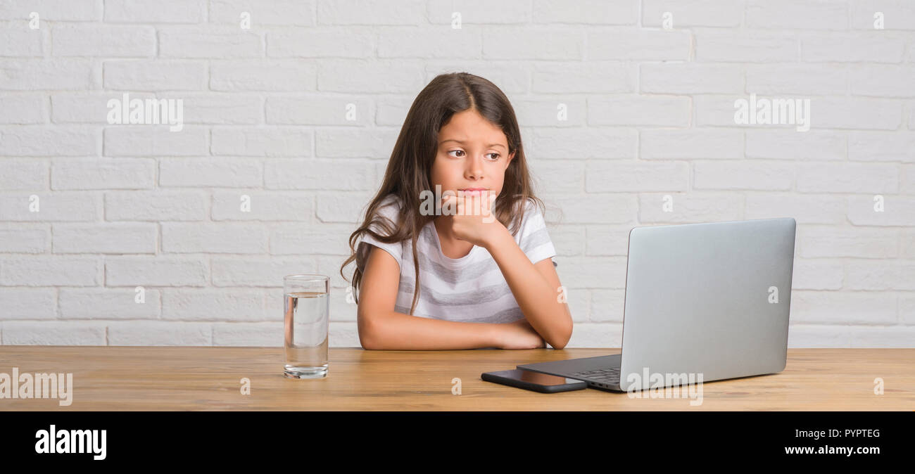 Young hispanic kid sitting on the table using computer laptop serious ...