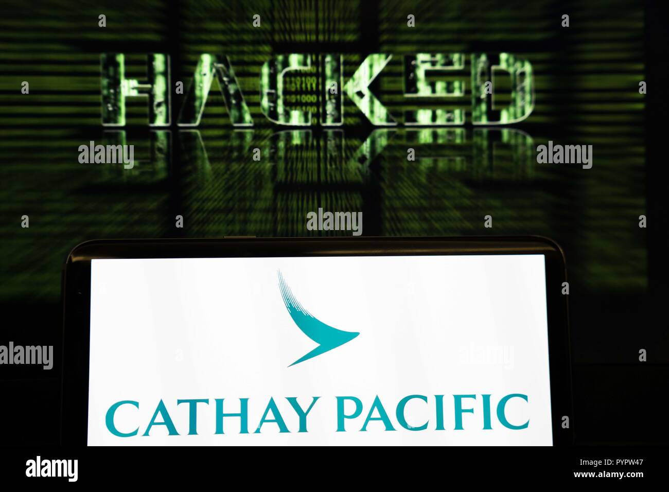 Cathay Pacific Logo displayed on a smartphone in front of a background which reads hacked. The Hong Kong based airline Cathay Pacific has reported that there has been a major data leak happened in march 2018 with data of around 9.4 million passengers was compromised during the breach, with 860,000 passport numbers, 245,000 Hong Kong identity card numbers, 403 expired credit card numbers and 27 credit card numbers without CVV being accessed. Stock Photo