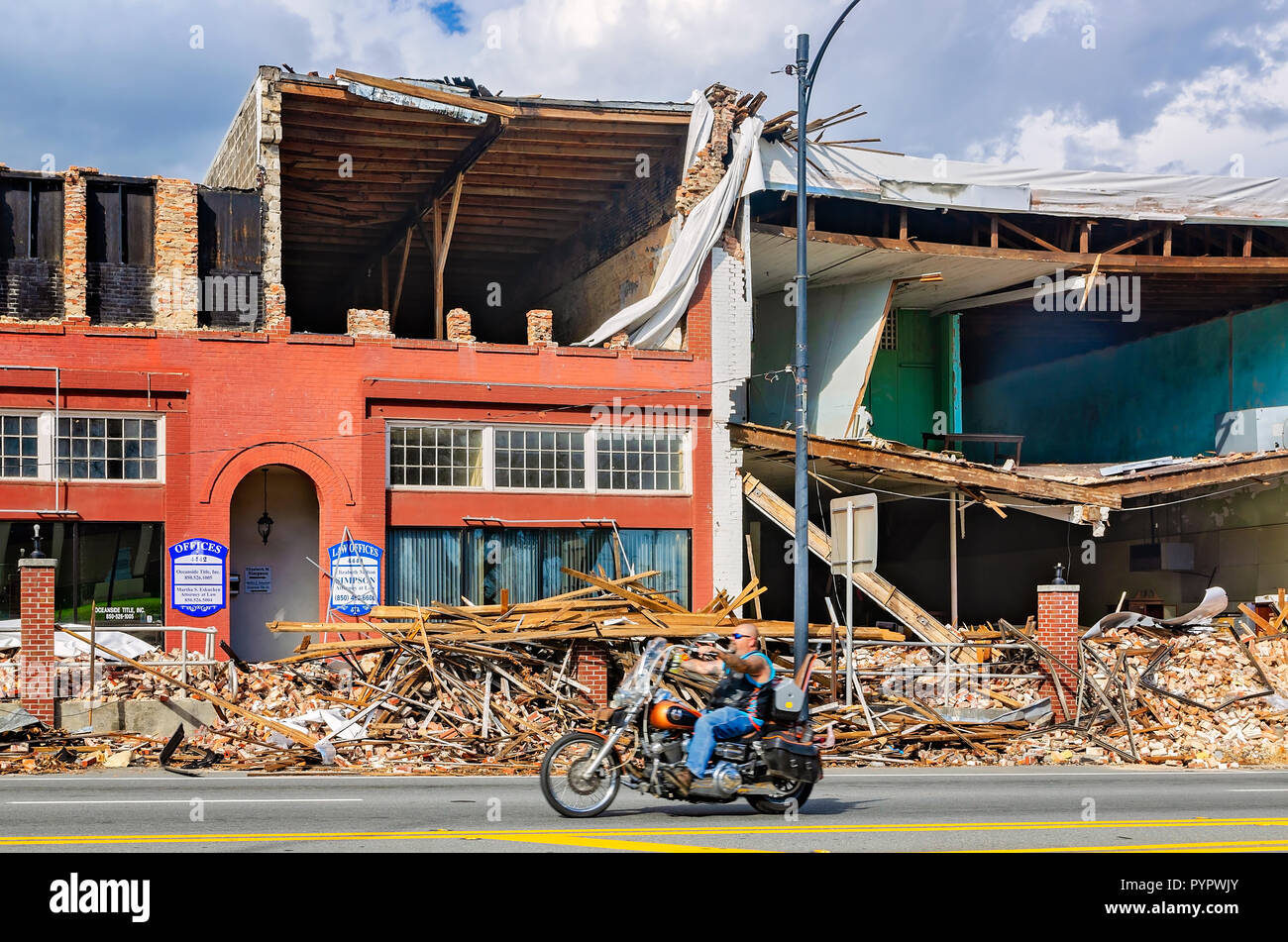A motorcyclist drives past damaged buildings on Lafayette Street after Hurricane Michael, Oct. 20, 2018, in Marianna, Florida. Stock Photo