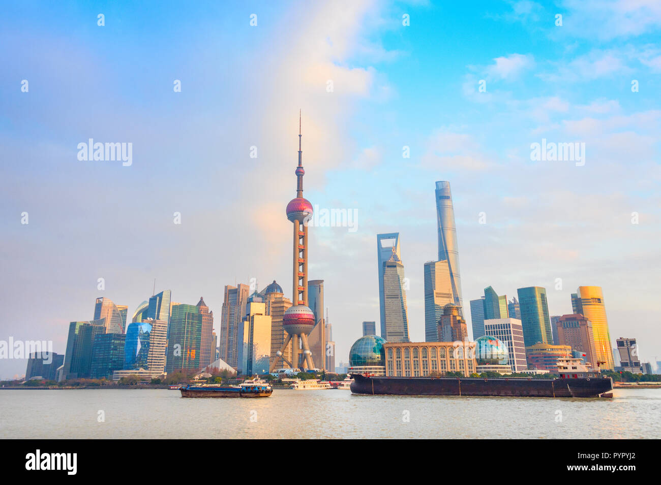 Skyline of Shanghai with barges by metropolis waterfront at sunset, China Stock Photo