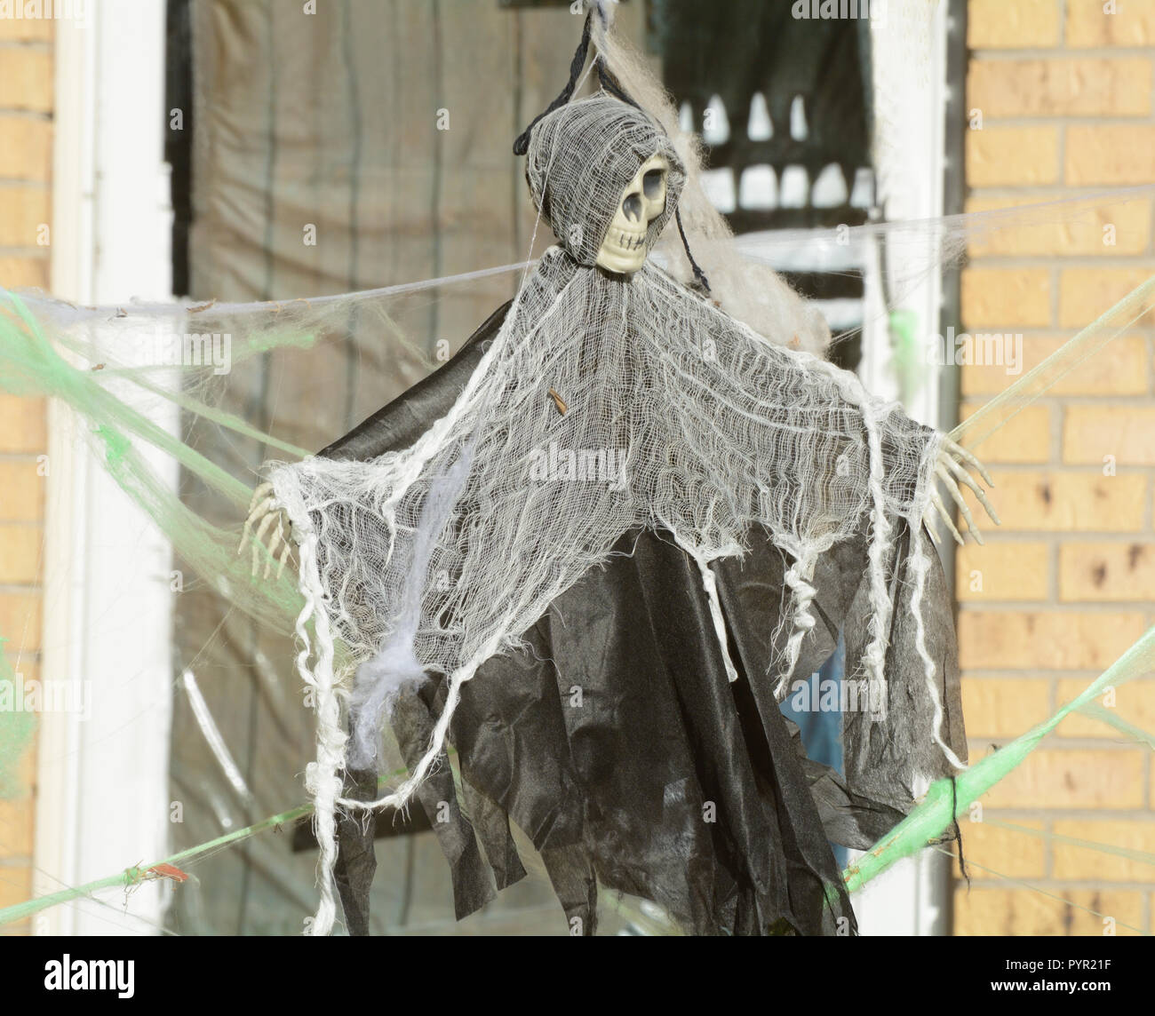Halloween skeleton decoration dressed in black robe with white shawl blocking access across doorway Stock Photo