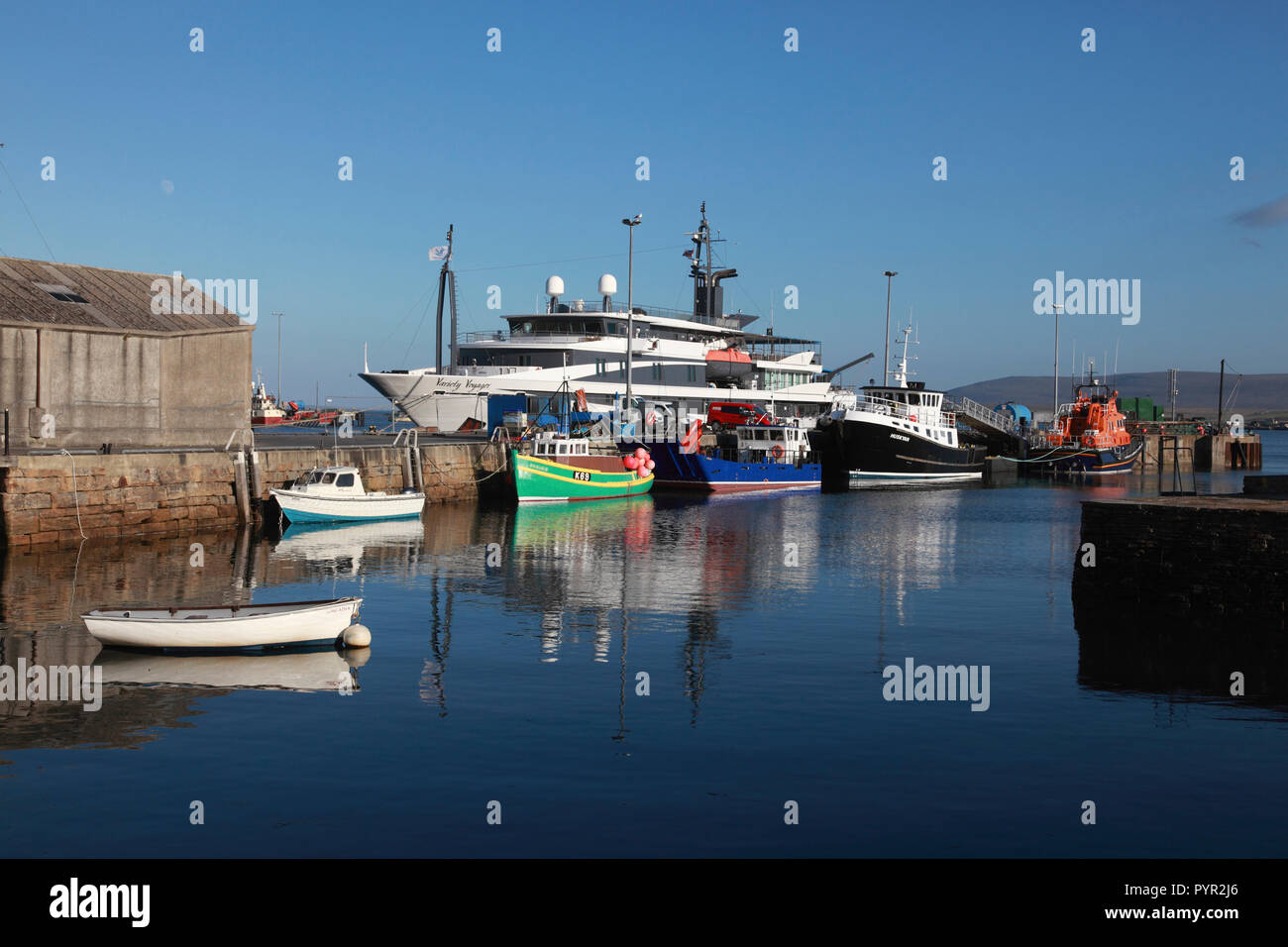 The harbour in Stromness, Orkney with fishing boats, the lifeboat and the passenger cruise ship, Variety Voyager Stock Photo