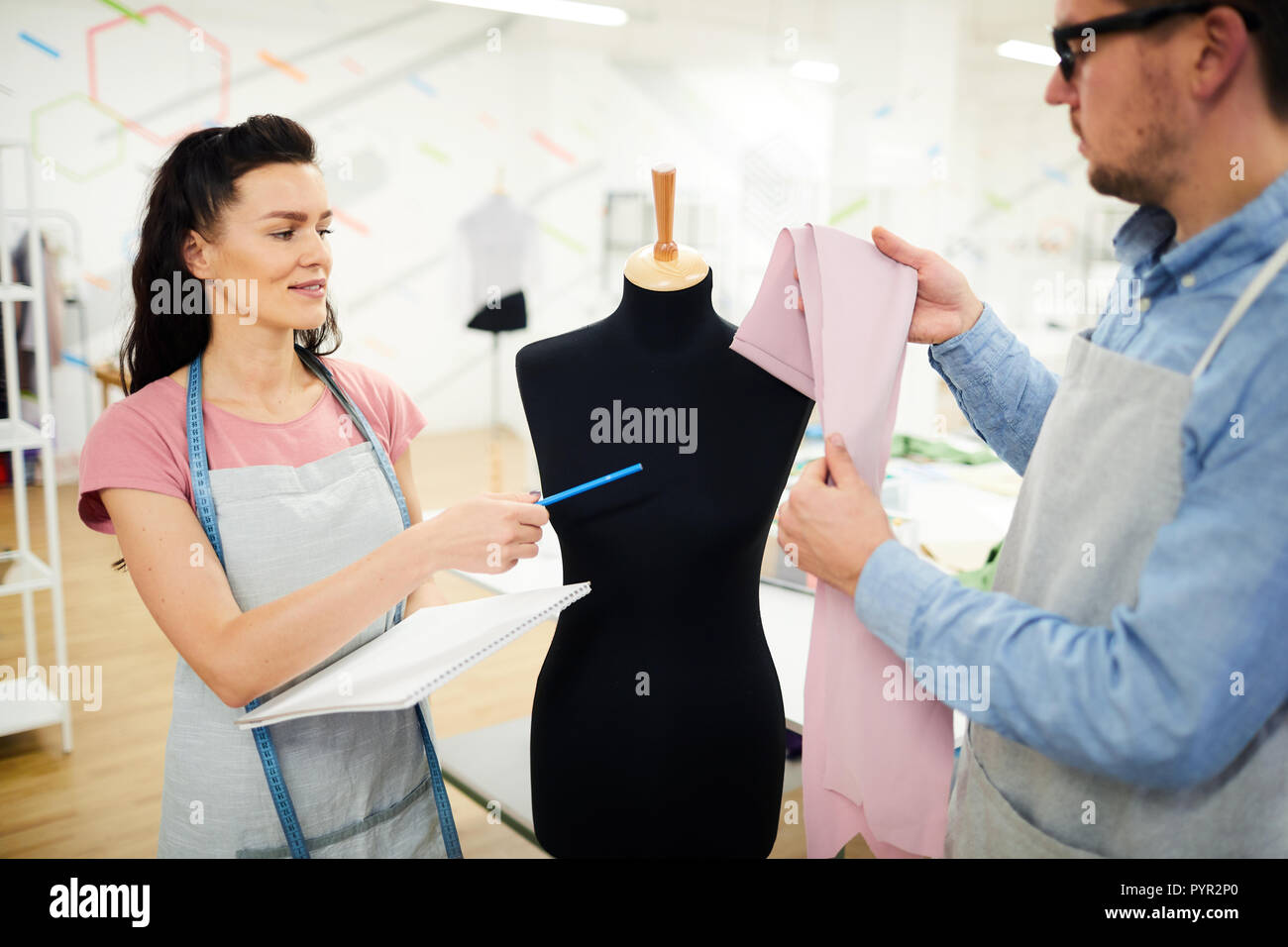 Young female student asking professional tailor about fabric Stock Photo