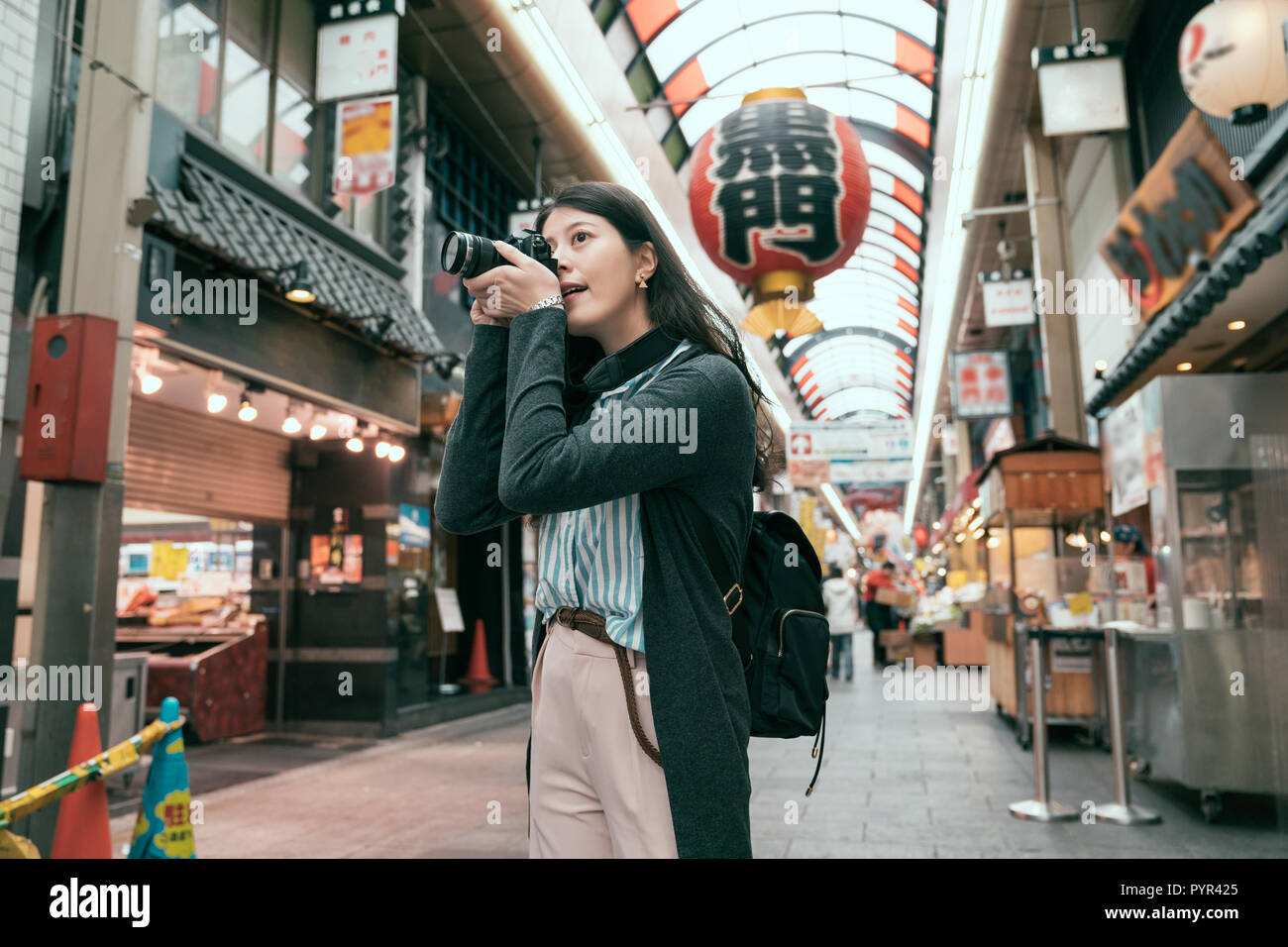 female traveler photographing japanese local lifestyle traditional market in Japan. lens man tourist hobby love taking picture by slr camera. Translat Stock Photo
