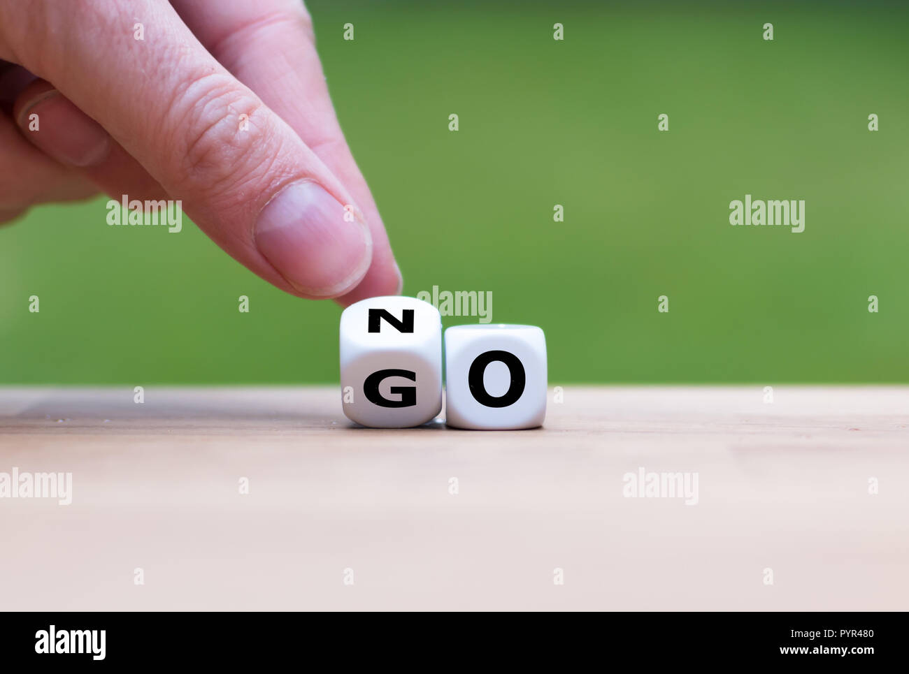 Hand is turning dice and changes the word go to no Stock Photo