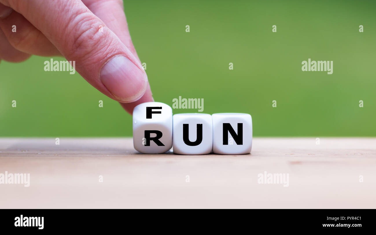 Hand is turning dice and changes the word Fun to Run Stock Photo