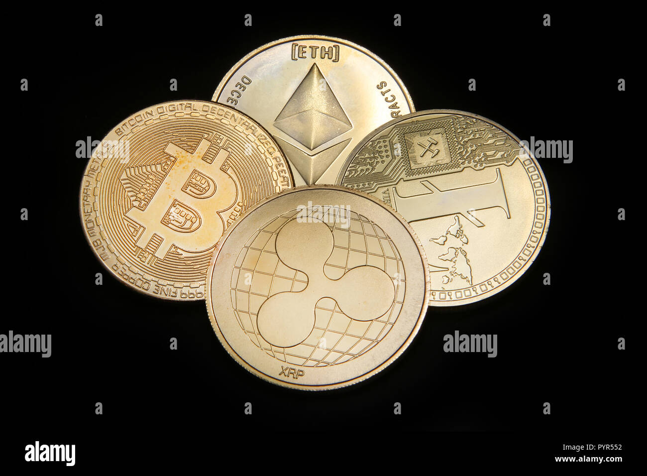 Litecoin, Ripple, Ethereum & Bitcoin gold coins representing cryptocurrenies against a black background. Stock Photo