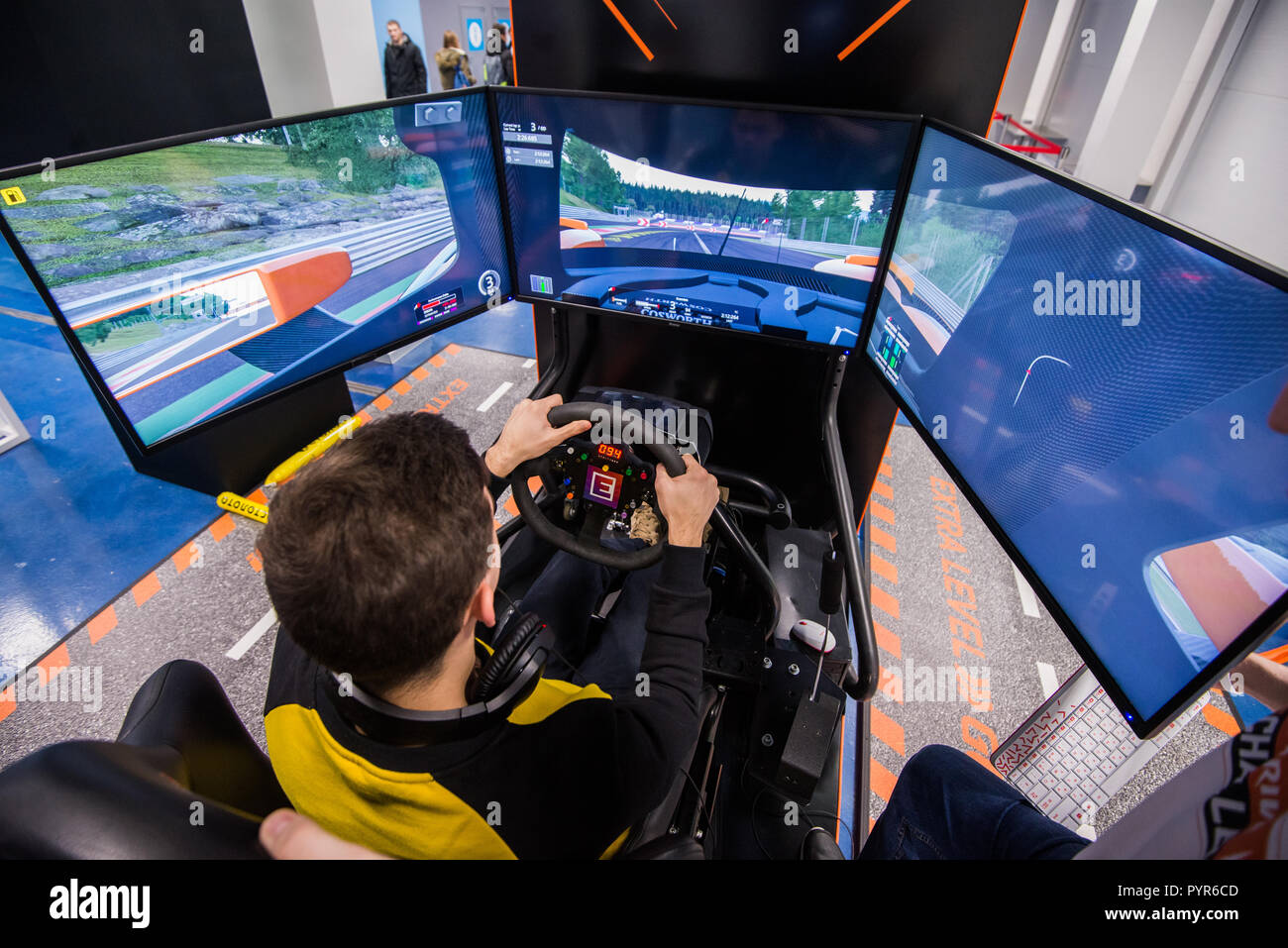 MOSCOW, RUSSIA - OCTOBER 27 2018. Young man plays on a computer racing simulator with big screens Stock Photo