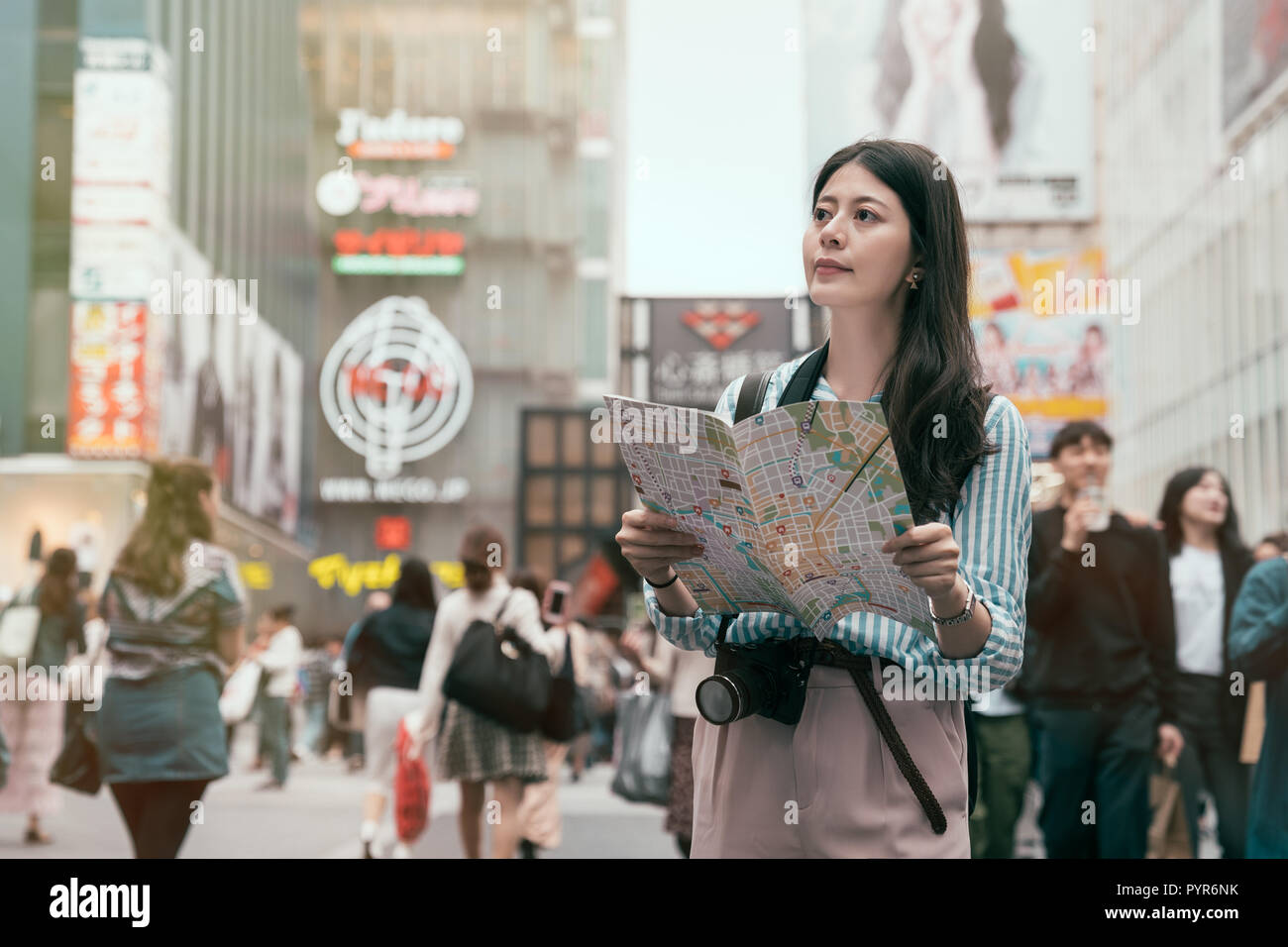Cheerful lady searching direction on location map while traveling abroad in japan. young traveler standing in the shopping center. Asia travel vacatio Stock Photo