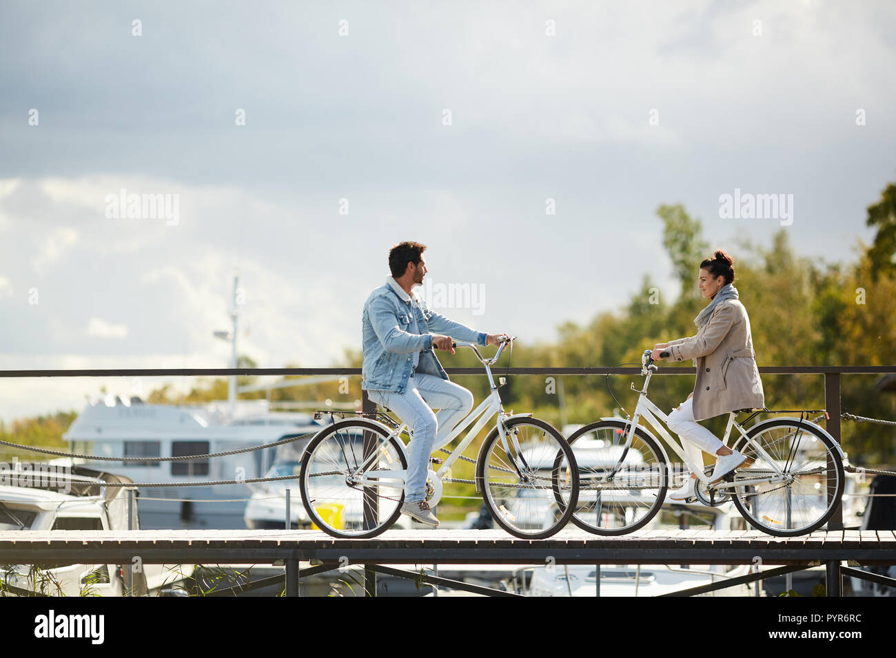 Beautiful couple on bicycles meeting on pier Stock Photo