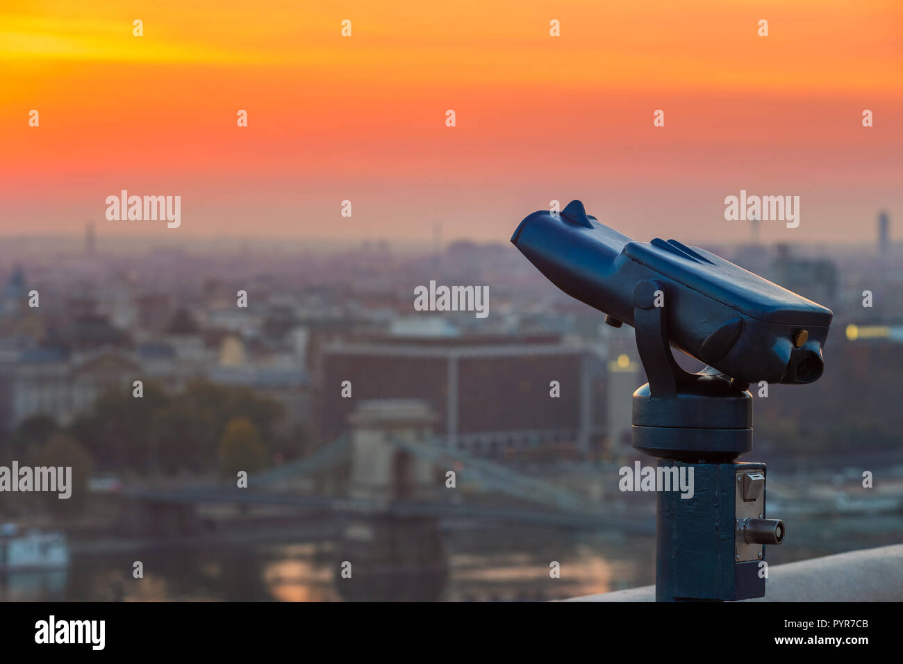 Budapest, Hungary - Blue binoculars with the view of Pest with Szechenyi Chain Bridge and beautiful golden sky at sunrise Stock Photo