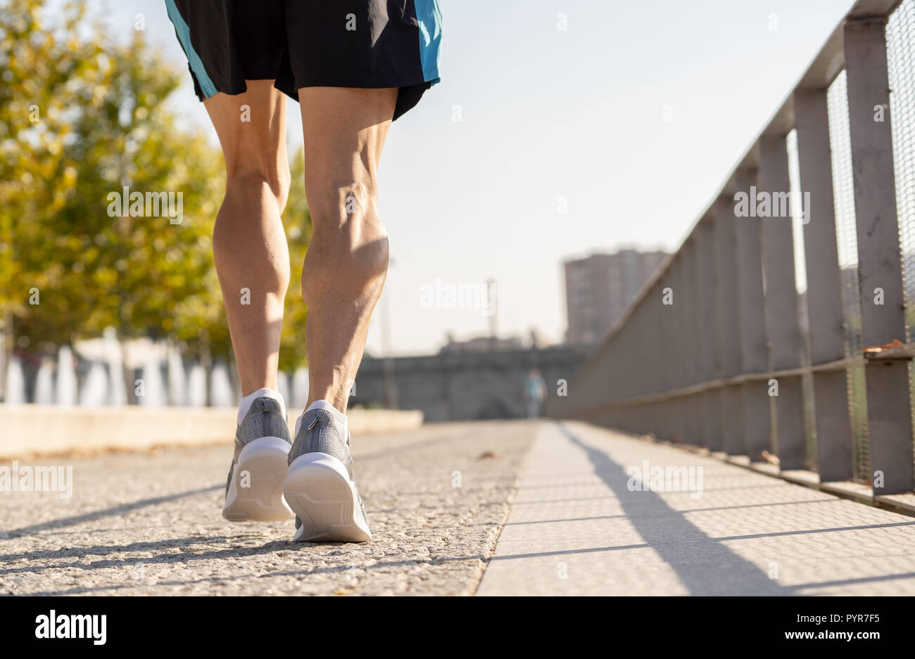 Close up image of strong athletic legs with ripped calf muscle of sport man running at sunset with copy space in urban city training Sport fitness Wor Stock Photo