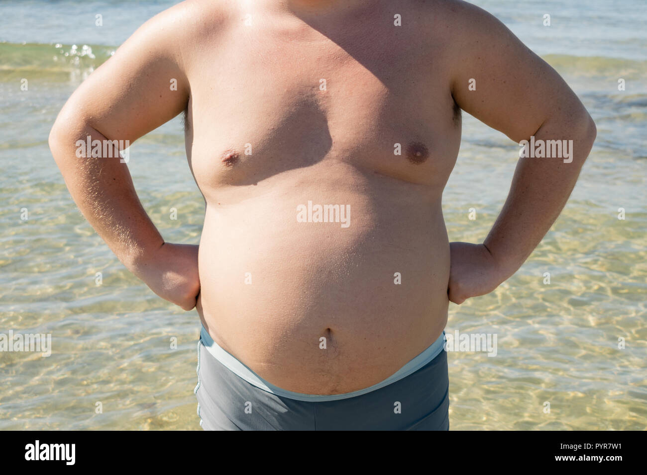a-fat-man-in-shorts-stands-on-the-shore-of-the-sea-sun-and-vacation-PYR7W1.jpg